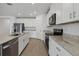 Well-lit kitchen featuring a central island, granite countertops, stainless steel appliances, and white cabinets at 1886 Draughton Dr, Zephyrhills, FL 33541