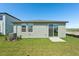 The backyard of the home features a grassy lawn and sliding glass door at 1876 Brekey Way, Zephyrhills, FL 33541