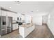 Modern kitchen with stainless steel appliances, granite countertops, and a center island, leading into an open living area at 1876 Brekey Way, Zephyrhills, FL 33541