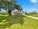 Charming single-story home featuring a sprawling green lawn, mature tree, and a welcoming front porch at 4000 Barbary Ln, North Port, FL 34287
