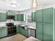 Well-equipped kitchen with stainless steel appliances and custom green cabinets at 4000 Barbary Ln, North Port, FL 34287