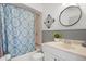 Classic bathroom with blue accents, including a patterned shower curtain and modern round mirror at 10280 97Th St, Largo, FL 33773