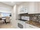 Open-concept kitchen with granite countertops, white appliances, and a mosaic tile backsplash at 500 The Esplanade N # 405, Venice, FL 34285