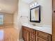 Bathroom with a dark framed mirror, wood cabinets, and an adjacent room at 4215 Edgewood Dr, Holiday, FL 34691