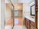 Bathroom with a dark framed mirror, wood cabinets, and an adjacent bedroom at 4215 Edgewood Dr, Holiday, FL 34691