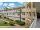 Well-maintained condo building featuring a clean facade, balconies, and manicured landscaping with tropical palm trees at 2071 Australia W Way # 27, Clearwater, FL 33763