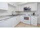 Bright kitchen with stainless steel appliances, granite countertops, white cabinets and tile floors at 3818 Moog Rd, Holiday, FL 34691