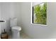 Bright powder room with floating toilet and a window with a tropical view at 415 N Bay Blvd, Anna Maria, FL 34216
