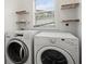 Laundry room features a washer, dryer, a window, and storage shelves at 4107 Mulgrave Ave, North Port, FL 34287