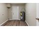 Utility room featuring modern water heater, door and durable wood flooring at 4702 E Idlewild Ave, Tampa, FL 33610