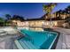 A resort-style pool at dusk with palm trees, cabanas, and lush landscaping at 606 Riviera Dunes Way # 604, Palmetto, FL 34221