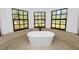 Bright bathroom featuring a modern soaking tub and large windows with a backyard view at 6604 Stafford Terrace Ave, Plant City, FL 33565