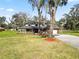 Two-story home featuring a long porch with landscaping, driveway, mature trees, and an attached garage at 6604 Stafford Terrace Ave, Plant City, FL 33565