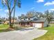 Two-story home with an attached garage, a long covered porch, mature trees, and driveway at 6604 Stafford Terrace Ave, Plant City, FL 33565