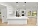 Bright open kitchen with island, white cabinets, stainless steel appliances, and light wood flooring at 6604 Stafford Terrace Ave, Plant City, FL 33565