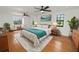 Bright main bedroom with hardwood floors, black framed windows, ceiling fans, and a teal accent blanket at 6604 Stafford Terrace Ave, Plant City, FL 33565
