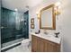 Modern bathroom with a glass-enclosed shower, wood vanity, and decorative gold-framed mirror at 7746 Westmoreland Dr, Sarasota, FL 34243