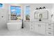 White bathroom featuring a soaking tub with black fixtures and a double vanity at 606 Indiana Ave, Crystal Beach, FL 34681