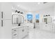 Bright bathroom with double vanity, soaking tub, and white marble floors at 606 Indiana Ave, Crystal Beach, FL 34681