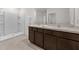 Bathroom featuring double sink vanity, framed mirrors, and a stand-up shower with white tile at 10523 Penny Gale Loop, San Antonio, FL 33576