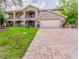 Two story home featuring mature landscaping and a paver driveway at 298 Gulfport Ln, Spring Hill, FL 34608