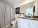 Stylish bathroom featuring a granite vanity, toilet, a shower curtain, and decorative art at 6744 Back Forty Loop, Zephyrhills, FL 33541