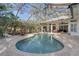 A beautiful kidney shaped pool in screened in lanai with brick patio and outdoor seating area at 4721 Country Manor Dr, Sarasota, FL 34233