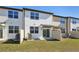 Rear view of townhomes featuring sliding glass doors, small patios, and grassy yards at 11836 Sylvia St, Dade City, FL 33525