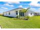 Beautiful backyard with green grass, landscaping, a white house, and a young palm tree at 16397 Preservation Blvd, Punta Gorda, FL 33982