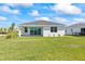 A well-maintained backyard with green lawn, a white home, and sliding glass doors leading to a covered patio at 16397 Preservation Blvd, Punta Gorda, FL 33982