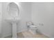 Simple powder room featuring a pedestal sink, toilet, and neutral tile flooring at 16397 Preservation Blvd, Punta Gorda, FL 33982