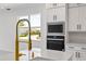 Modern kitchen close-up featuring white countertops, stainless steel appliances, and a stylish faucet at 16397 Preservation Blvd, Punta Gorda, FL 33982
