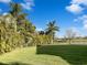 A lush green lawn and tropical trees create a private backyard oasis with water view beyond the black metal fence at 6113 Shadowlake Dr, Apollo Beach, FL 33572