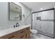 Bathroom with a wood vanity, white marble counter, black fixtures, and tiled glass shower at 530 Foxglove Rd, Venice, FL 34293