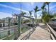 Exterior features a dock with boat lift, wooden planks, and waterfront views, surrounded by lush palm trees on a sunny day at 318 182Nd E Ave, Redington Shores, FL 33708