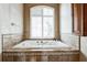 Relaxing bathroom featuring a large tub with elegant tile surround and natural light from the window at 4319 Gentrice Dr, Valrico, FL 33596