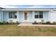 Charming home exterior featuring a light blue facade, a pink front door, and well-maintained landscaping at 511 Sharon Cir, Port Charlotte, FL 33952