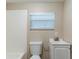 Bright bathroom features a white tiled shower, toilet and vanity with a sink, complemented by a window with blinds at 2634 E 38Th Ave, Tampa, FL 33610
