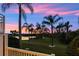 Scenic backyard view with palm trees, lush green grass, and a tranquil lake under a colorful sunset sky at 4324 Spinnaker Cove Ln, Tampa, FL 33615