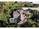 Aerial view of a private residence featuring a screened-in pool, lush greenery, and detailed roof design at 7705 Weeping Willow Cir, Sarasota, FL 34241