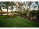 Lush backyard showcasing manicured lawn, tropical trees, and a glimpse of the serene lake at 7705 Weeping Willow Cir, Sarasota, FL 34241