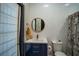 Stylish bathroom featuring a blue vanity, toilet, round mirror, and a shower at 7705 Weeping Willow Cir, Sarasota, FL 34241