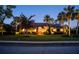 Charming home at twilight featuring lush landscaping and a brightly lit, arched front door at 7705 Weeping Willow Cir, Sarasota, FL 34241