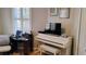 Bedroom or office space with large window, wood floors, white piano and desk at 12209 Putter Green Ct, New Port Richey, FL 34654