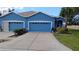 Charming blue home featuring a driveway and attached garage, complete with well-maintained landscaping at 12209 Putter Green Ct, New Port Richey, FL 34654