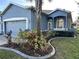 Charming blue home featuring a well-manicured lawn and a welcoming front entrance and attached garage at 12209 Putter Green Ct, New Port Richey, FL 34654