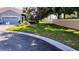 View of the beautifully landscaped front yard with lush green grass surrounding the charming blue home at 12209 Putter Green Ct, New Port Richey, FL 34654