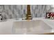 Farm sink with a white countertop, brass faucet, and mosaic backsplash at 12209 Putter Green Ct, New Port Richey, FL 34654