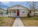 Inviting home featuring a red door, covered porch, and well-maintained lawn with mature foliage at 3408 Phillips St, Tampa, FL 33619