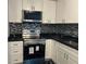 Modern kitchen features white cabinets, stainless steel appliances, and black countertops with a backsplash at 501 Knights Run Ave # 2106, Tampa, FL 33602
